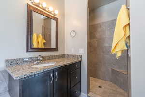 Full bath featuring vanity and tiled shower
