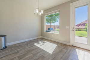Unfurnished dining area featuring a chandelier and wood finished floors