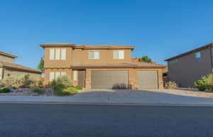View of front of property featuring driveway, stucco siding, stone siding, a garage, and an attached garage