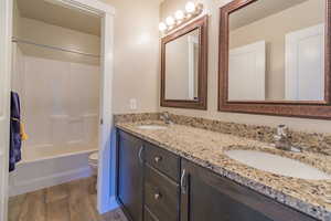 Bathroom with double vanity, wood finished floors, and shower / bath combination