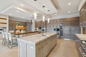 Kitchen featuring a spacious island, recessed lighting, hanging light fixtures, light stone countertops, and appliances with stainless steel finishes