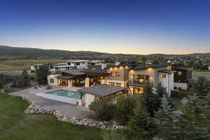 Back of property featuring a patio area, an outdoor pool, a mountain view, stucco siding, and a residential view