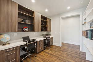 Office space with built in desk, dark wood-style floors, recessed lighting, and built in features