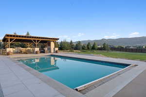View of swimming pool with a mountain view, exterior kitchen, and a patio