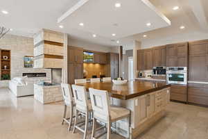 Kitchen featuring recessed lighting, wooden counters, a breakfast bar area, a stone fireplace, and open floor plan