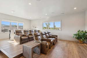 Home theater room featuring plenty of natural light, light wood-style floors, and recessed lighting