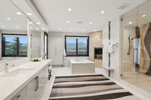 Bathroom with a stall shower, vanity, a garden tub, a fireplace, and recessed lighting