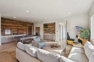 Living room featuring wood walls, wet bar, recessed lighting, light wood-style floors, and pool table