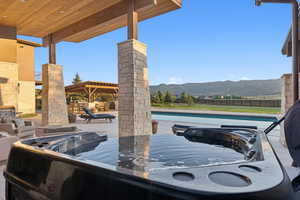 View of patio / terrace featuring a hot tub, a mountain view, an outdoor pool, and a grill