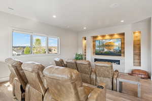 Home theater room with recessed lighting, a glass covered fireplace, and light wood-style floors