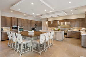 Kitchen with a spacious island, tasteful backsplash, high end appliances, recessed lighting, and a breakfast bar area