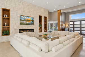 Tiled living room with built in shelves, a fireplace, recessed lighting, and a towering ceiling