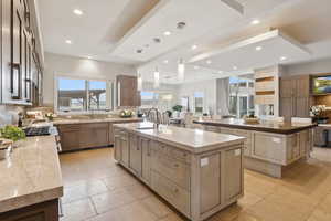 Kitchen featuring a large island, recessed lighting, light stone counters, decorative light fixtures, and stainless steel gas range