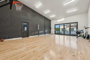 Workout area featuring wood finished floors, high vaulted ceiling, and wood walls
