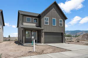 View of front of home featuring a shingled roof, a garage, board and batten siding, concrete driveway, and a mountain view