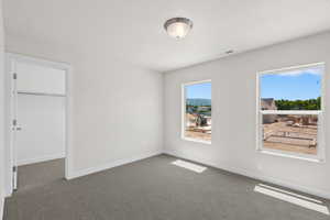 Carpeted empty room featuring baseboards and a textured ceiling