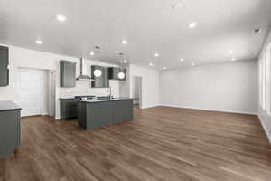 Kitchen with dark countertops, decorative backsplash, a center island with sink, dark wood-style floors, and recessed lighting