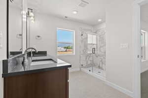 Bathroom featuring double vanity, a marble finish shower, and tile patterned floors