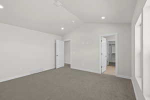 Unfurnished Primary bedroom with carpet floors, vaulted ceiling, a spacious closet, and recessed lighting