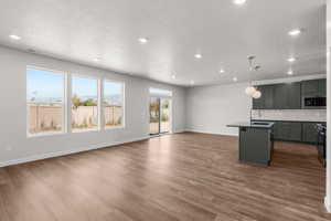 Kitchen featuring a textured ceiling, open floor plan, dark countertops, recessed lighting, and stainless steel appliances