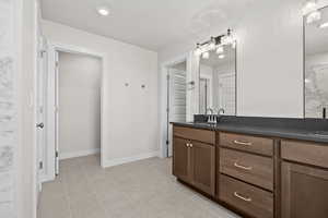 Bathroom with double vanity, recessed lighting, and a closet