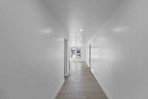 Hall with light wood finished floors and recessed lighting