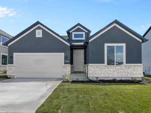 View of front of house with stone siding, a front lawn, an attached garage, and stucco siding