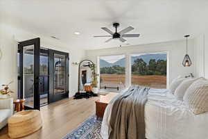 Bedroom with multiple windows, access to outside, wood finished floors, recessed lighting, and french doors