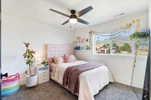 Carpeted bedroom with a ceiling fan and a mountain view