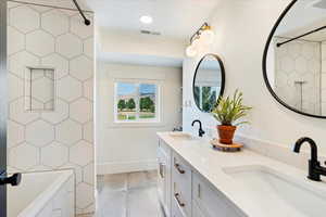 Full bathroom featuring double vanity, a tub, and tiled shower