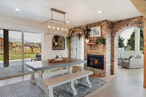Dining area featuring plenty of natural light, light wood-style floors, a brick fireplace, and recessed lighting