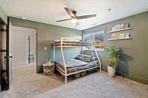 Bedroom featuring carpet, a textured wall, a textured ceiling, and ceiling fan