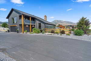 View of front of property with a mountain view, a chimney, an attached garage, and a balcony