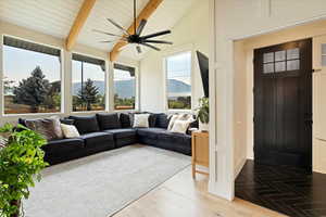 Living room with plenty of natural light, light wood-style floors, a ceiling fan, and wood ceiling
