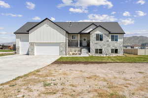 View of front of property with stone siding, an attached garage, driveway, board and batten siding, and a mountain view