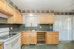 Kitchen with light brown cabinetry, white electric range, and open shelves