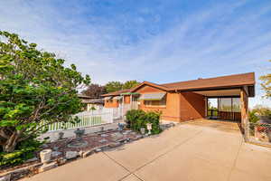 Back of property with driveway, brick siding, and a carport