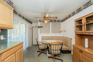 Carpeted dining room featuring ceiling fan