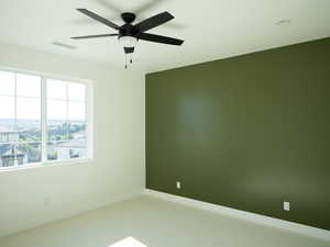 Carpeted spare room with ceiling fan and baseboards