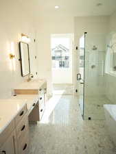 Bathroom featuring vanity, a soaking tub, a tile shower, and recessed lighting