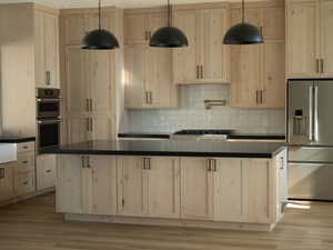 Kitchen featuring light brown cabinets, dark countertops, appliances with stainless steel finishes, and a center island