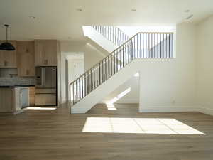 Stairs with wood finished floors, recessed lighting, and a high ceiling