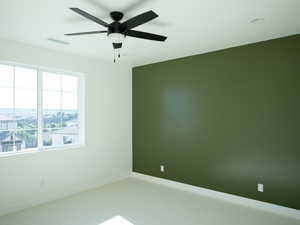 Carpeted spare room with baseboards and ceiling fan