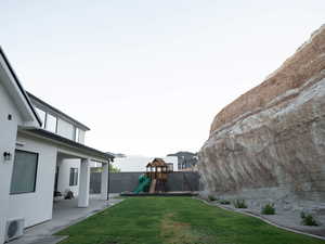 Fenced backyard with a playground and a patio area