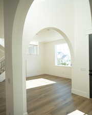 Unfurnished room with healthy amount of natural light, wood finished floors, and arched walkways