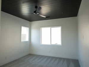 Empty room with light carpet, ceiling fan, and wooden ceiling