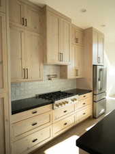 Kitchen featuring light brown cabinetry, tasteful backsplash, dark countertops, appliances with stainless steel finishes, and recessed lighting