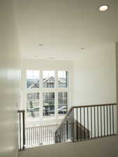 Hall with recessed lighting and an upstairs landing