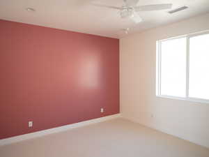 Unfurnished room featuring light carpet and a ceiling fan