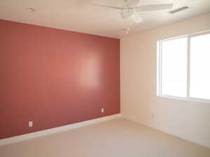 Carpeted empty room featuring a ceiling fan and baseboards